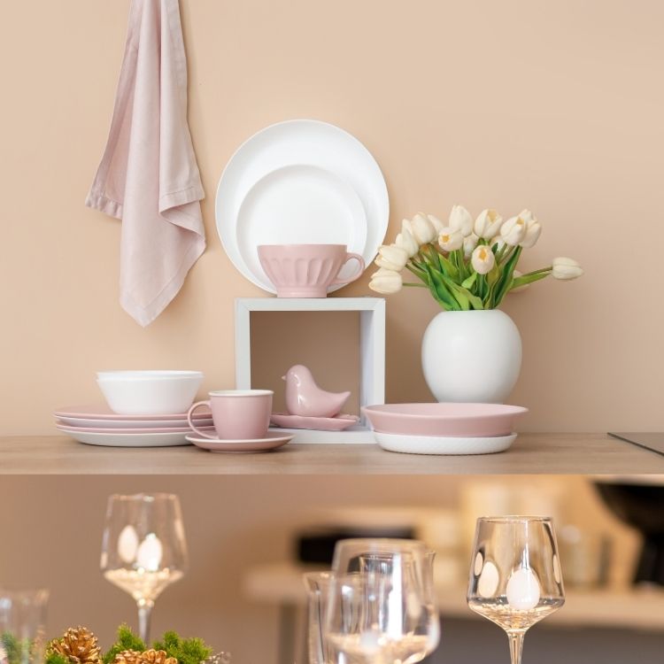 Elegant table setting with pink and white dinnerware, a bird figurine, and a vase of tulips on a beige background.