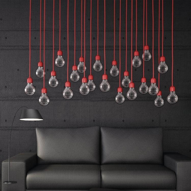 A black couch featuring red pillows, complemented by a red pendant light hanging in a farmhouse-inspired room.