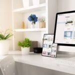 A modern workspace featuring a computer, tablet, and smartphone displaying an online shopping site, surrounded by plants and decor.